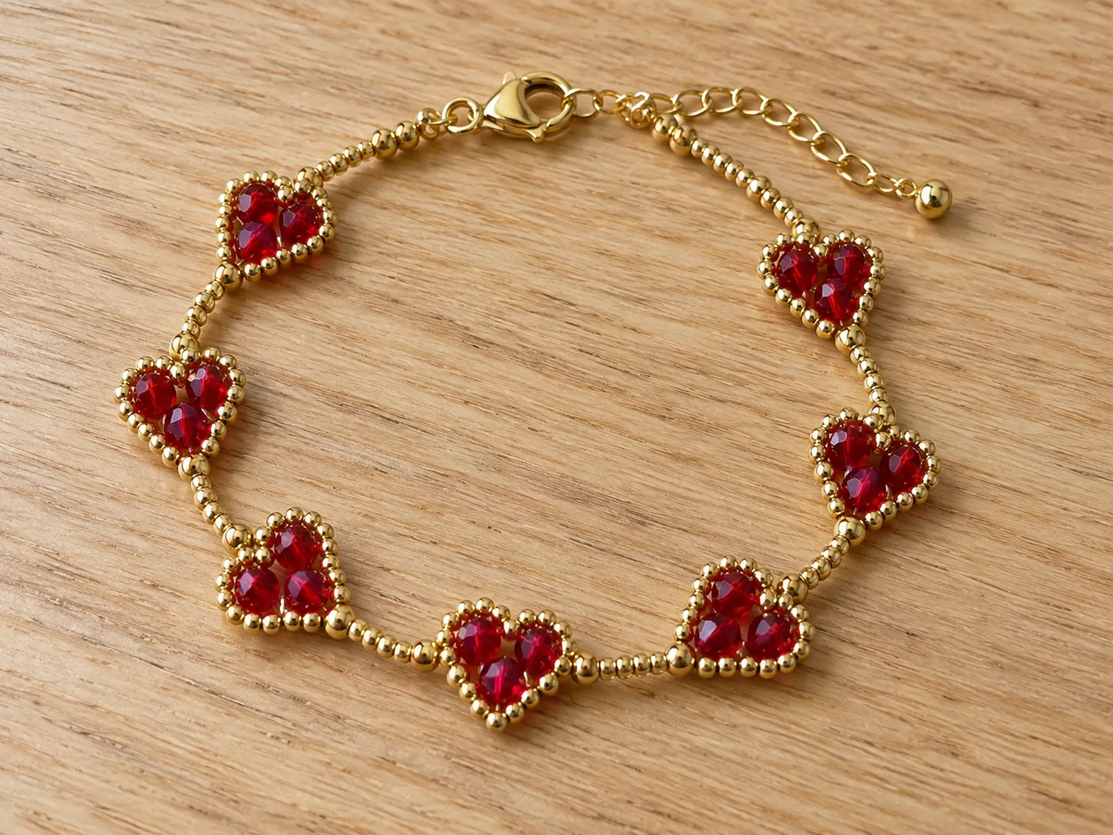 KI-generiertes Bild: fertiges Herz-Armband aus rubinroten Glasschliffperlen und goldenen Rocailles auf hellem Holztisch