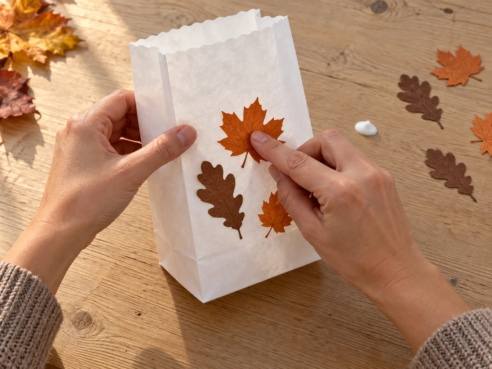 KI-generiertes Bild: Hände kleben orange und braune ausgestanzte Papierblätter auf eine weiße Papiertüte